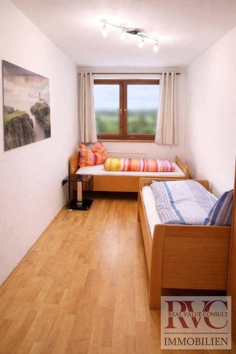 Helles Kinder- oder Gästezimmer mit zwei Einzelbetten und Fensterblick auf die Landschaft.