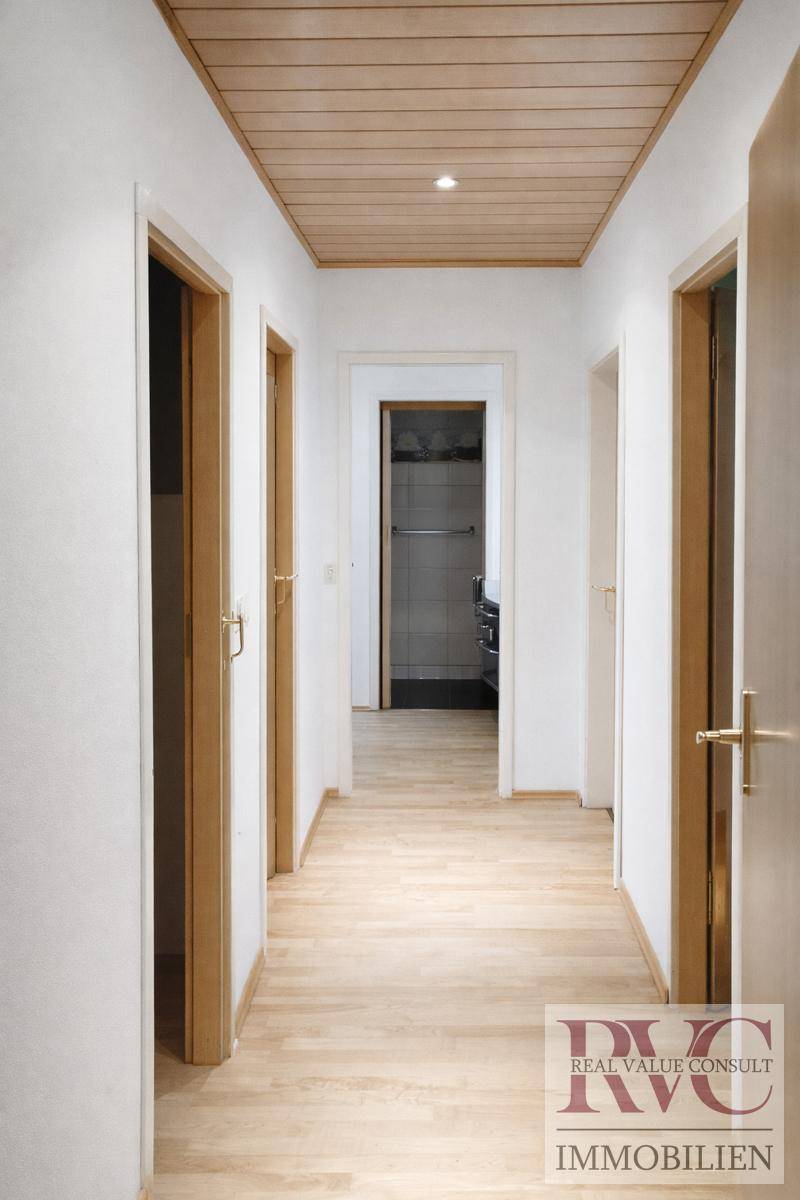 Heller Flur mit Holzdeckenverkleidung und hellem Laminatboden, der zu weiteren Räumen führt.