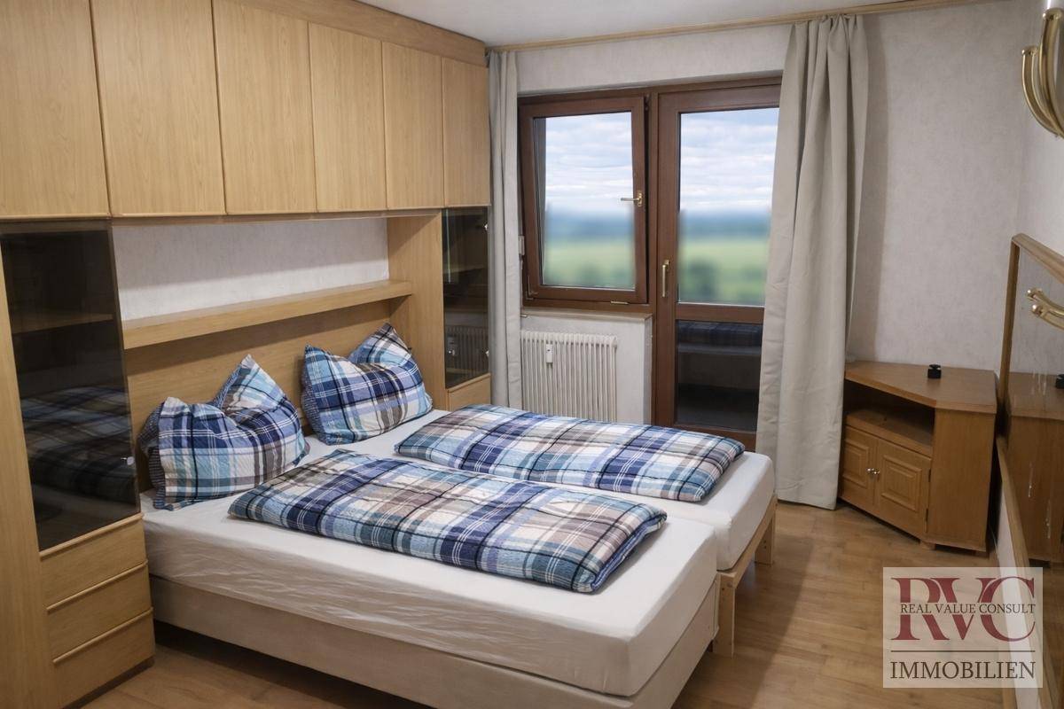 Schlafzimmer mit zwei Einzelbetten, Einbauschränken und Fenster mit Blick ins Grüne.
