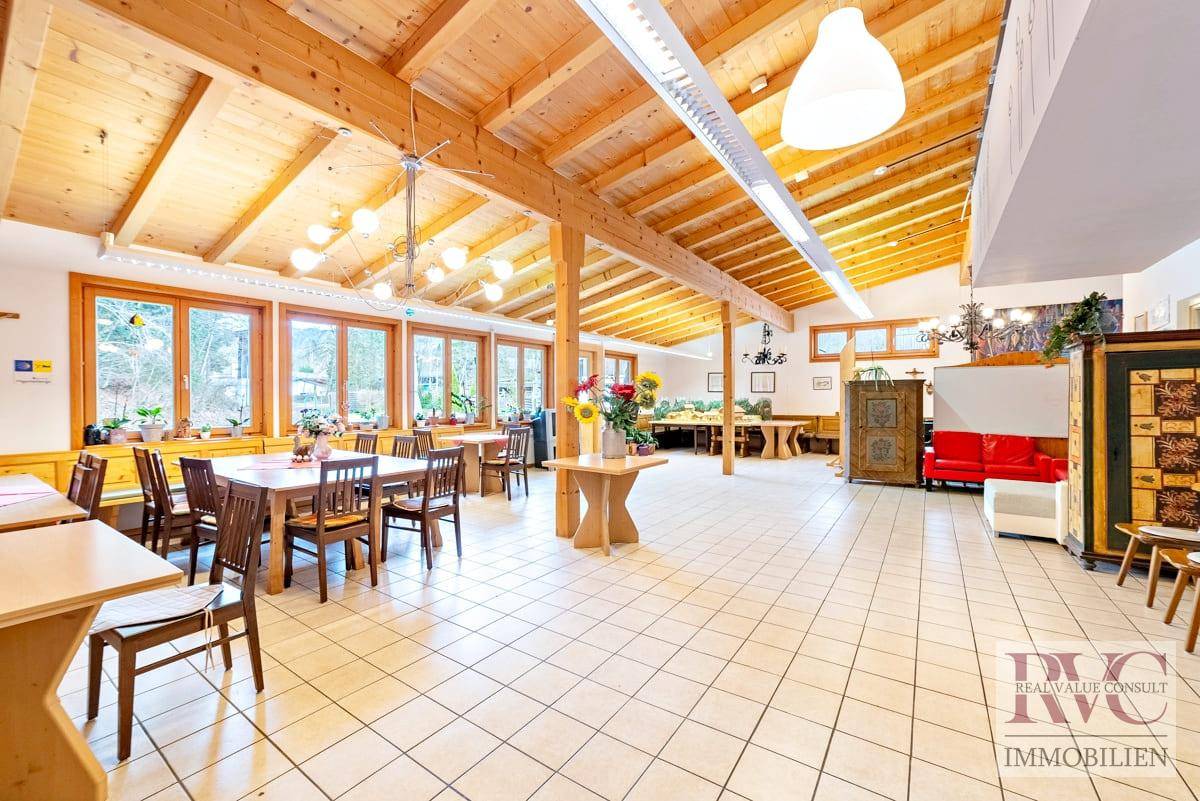 Großer, heller Gemeinschaftsraum mit hohen Holzdecken, Fliesenboden und vielen Fenstern.