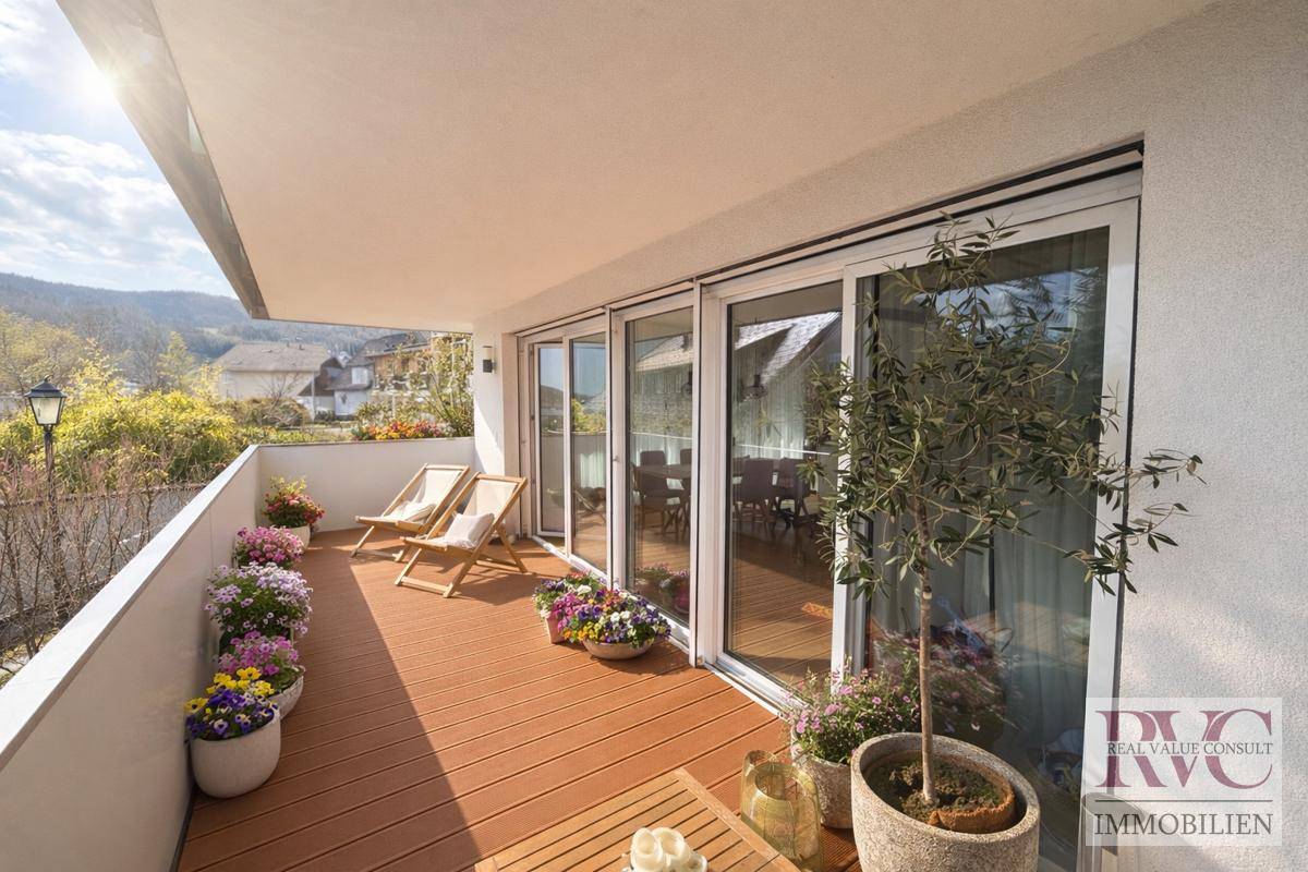 Geräumiger Balkon mit Holzboden, Pflanzen und Liegestühlen für entspannte Stunden.