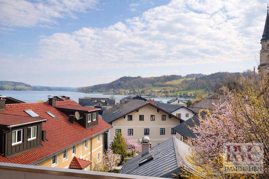 Panoramablick vom Balkon über eine malerische Stadt, See und umliegende Hügel.