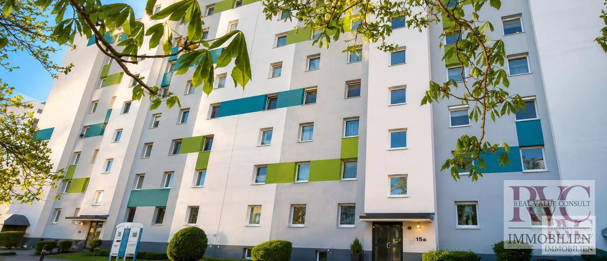 Mehrstöckiges Wohngebäude mit farbigen Akzenten an der Fassade und grüner Umgebung.