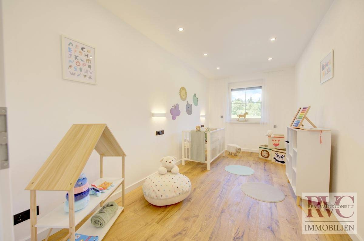 Geräumiges Kinderzimmer mit viel Tageslicht, Spielzeug und Blick auf die Natur.