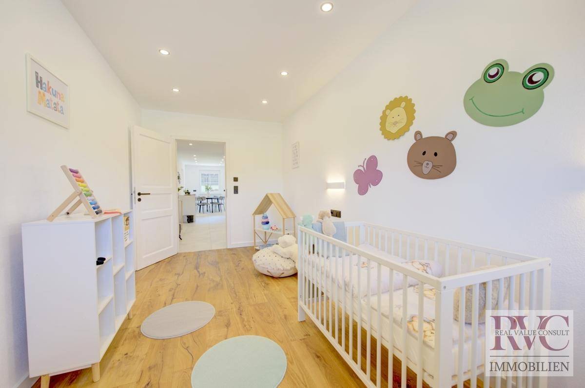 Freundliches Kinderzimmer mit Holzboden, Babybett und bunten Wanddekorationen.