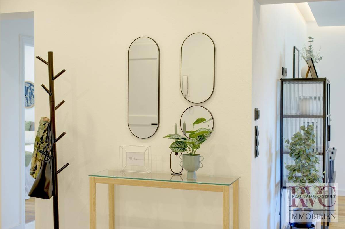 Moderner Flur mit Spiegeln, Konsole und Garderobe, der zu weiteren Räumen führt.