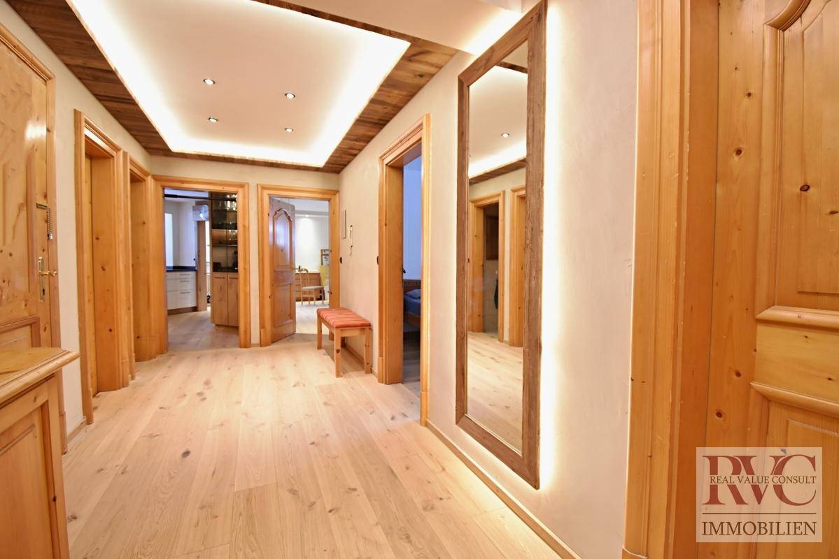 Heller Flur mit Holztüren, Deckenbeleuchtung und einem großen Wandspiegel.