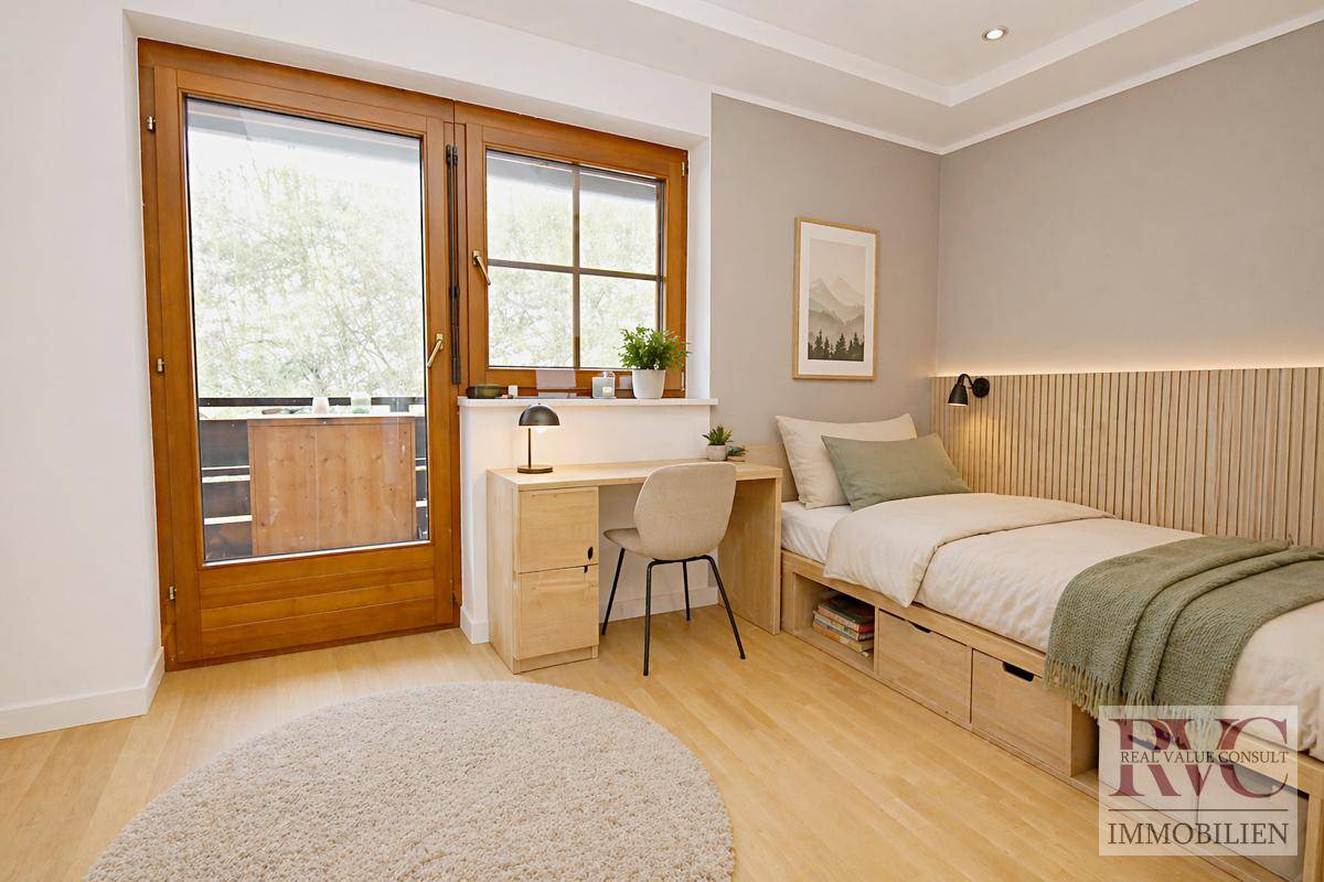 Helles Schlafzimmer mit Einzelbett, Schreibtisch und Zugang zu einem Balkon.