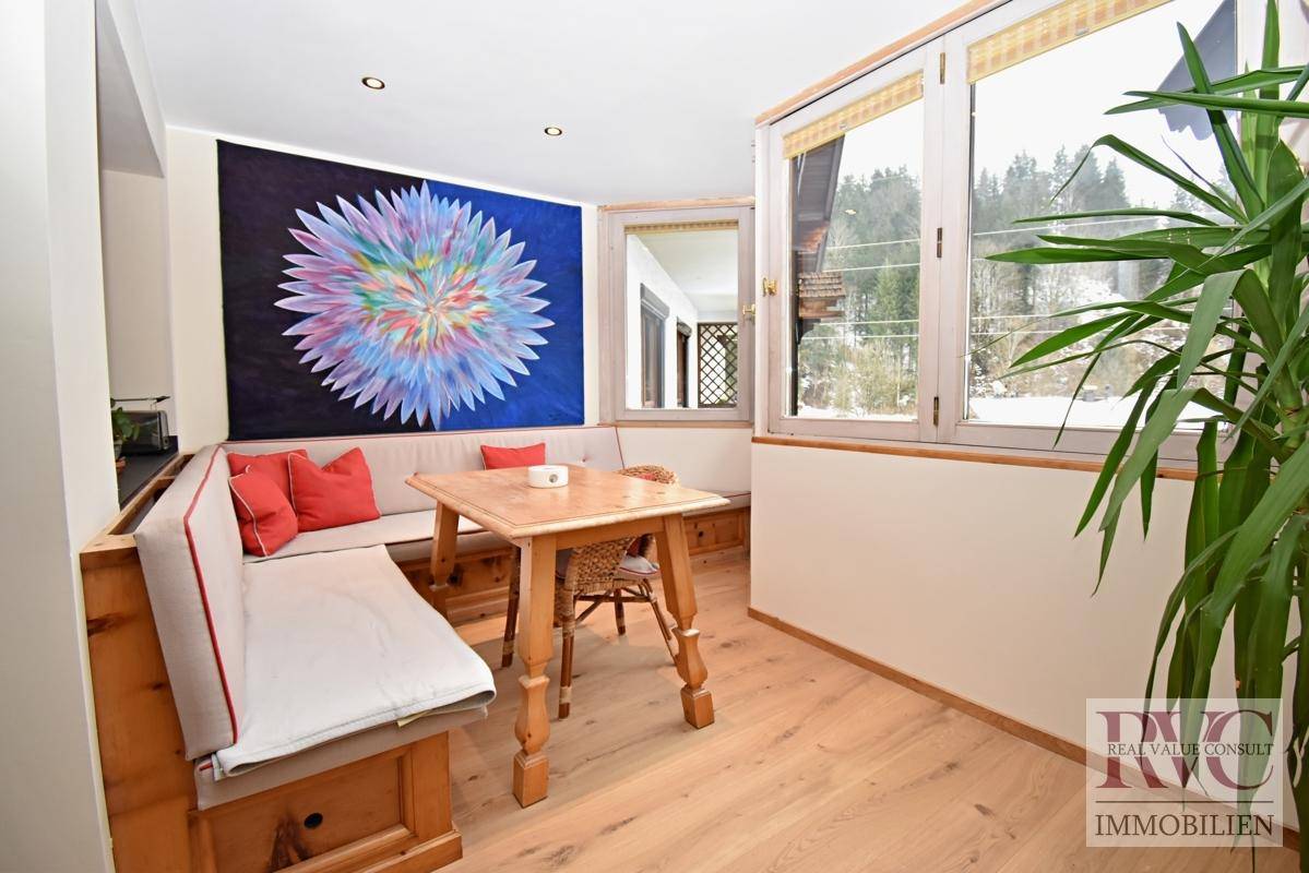 Heller Essbereich mit Holztisch, Eckbank und farbenfrohem Kunstwerk an der Wand.