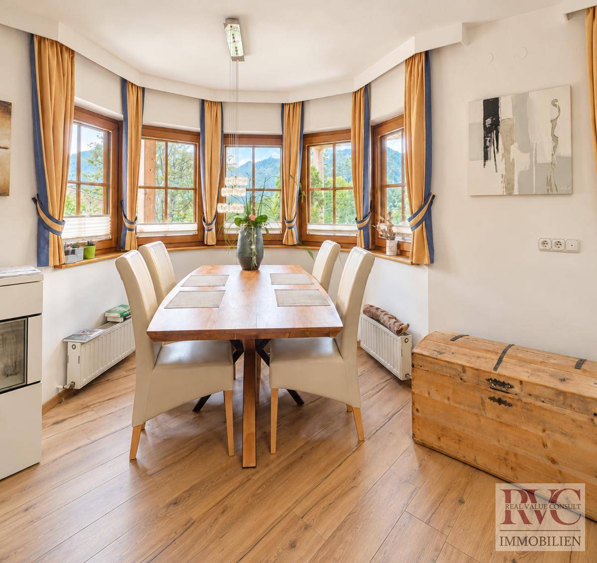 Gemütlicher Essbereich mit Holztisch, Stühlen und Panoramafenstern mit Bergblick.