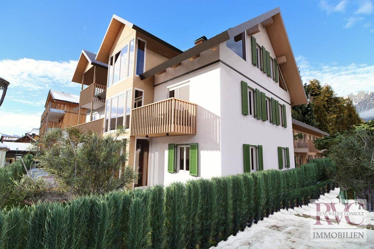 Seitenansicht der Wohnanlage mit Holzbalkonen, grünen Fensterläden und verschneiter Umgebung.