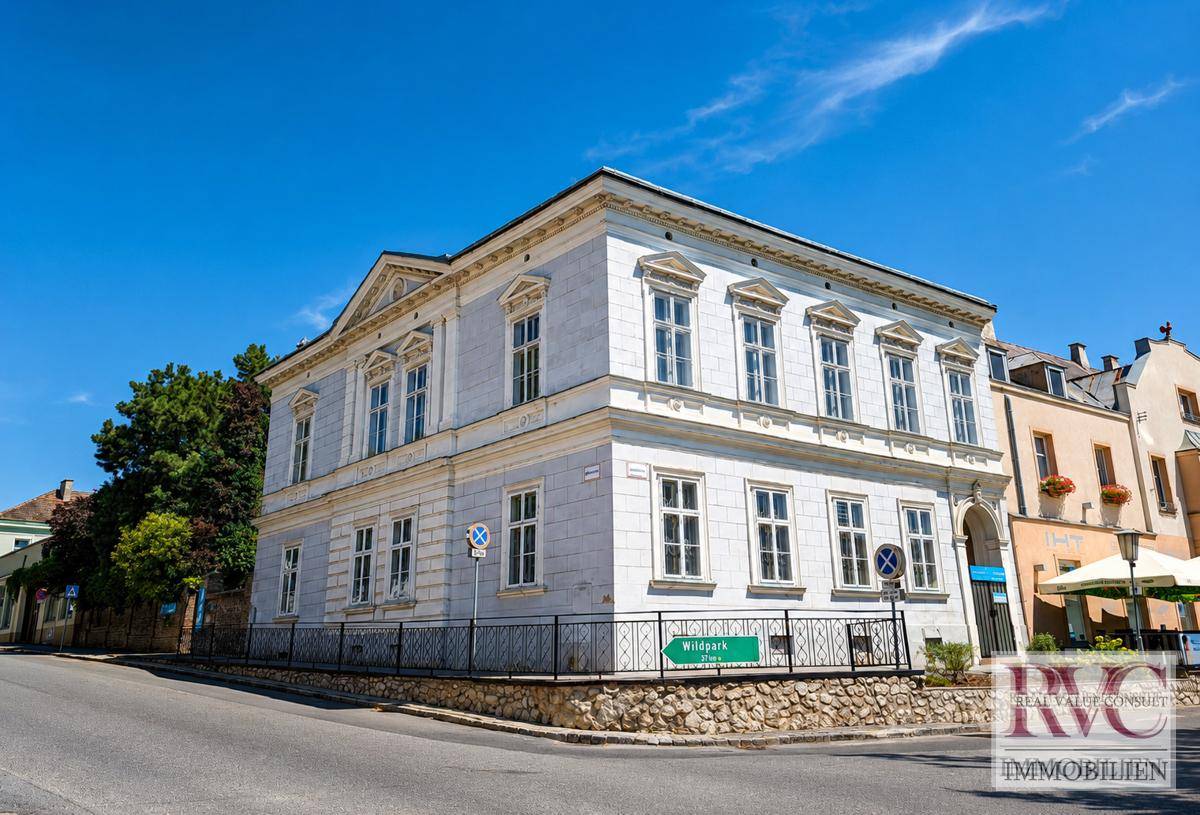 Ansicht des historischen Gebäudes von der Straße aus, mit klassischer Architektur und blauer Himmel.