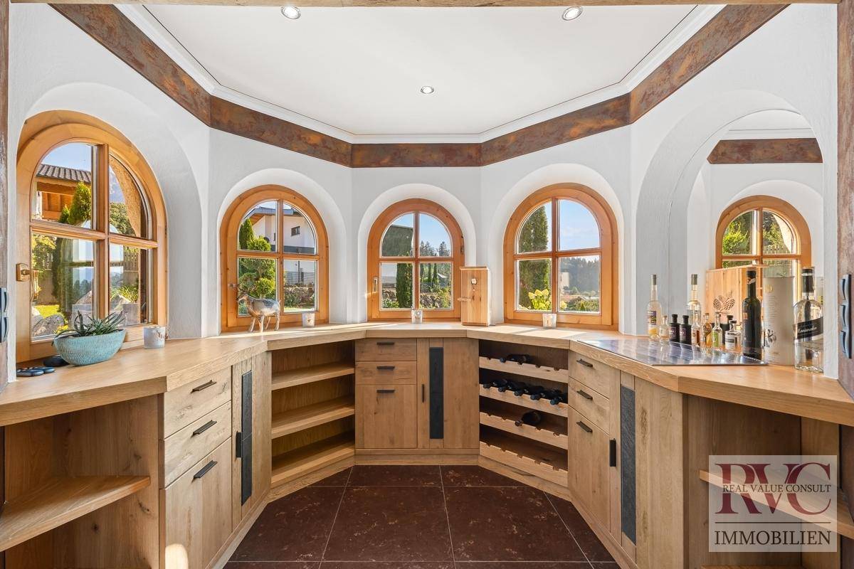 Stilvolle Bar mit Weinfächern, Holzeinbauten und charmanten Rundbogenfenstern mit Blick ins Grüne.