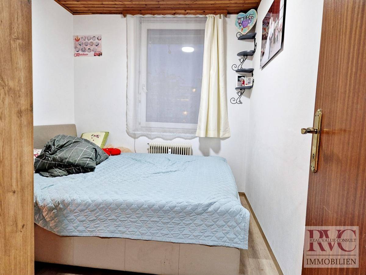 Schlafzimmer mit Doppelbett, Fenster und rustikaler Holzdeckenverkleidung.
