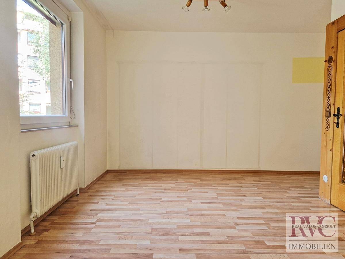 Geräumiges Zimmer mit Parkettboden und großem Fenster.