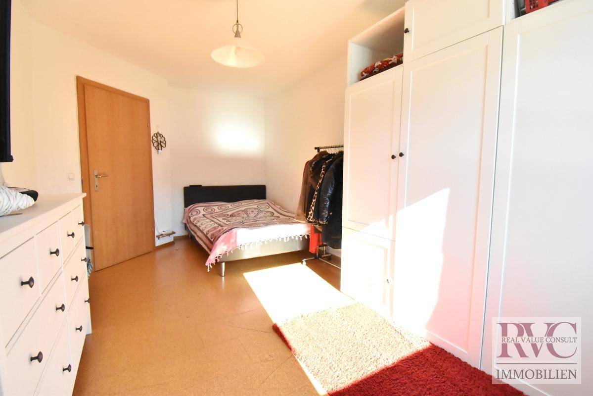 Helles Schlafzimmer mit Korkboden, weißem Kleiderschrank und viel natürlichem Sonnenlicht.
