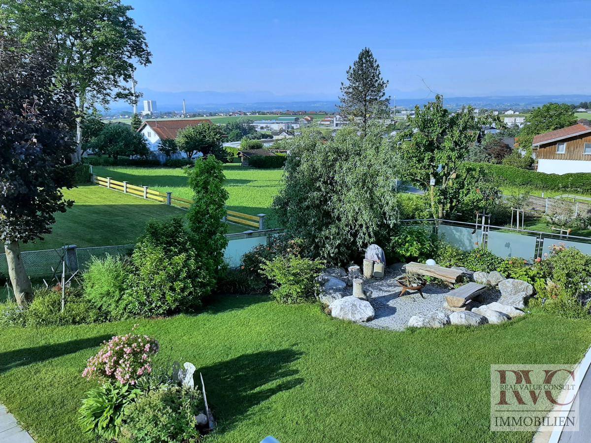Großer Garten mit Feuerstelle, weitläufigem Rasen, Bäumen und Panoramablick.