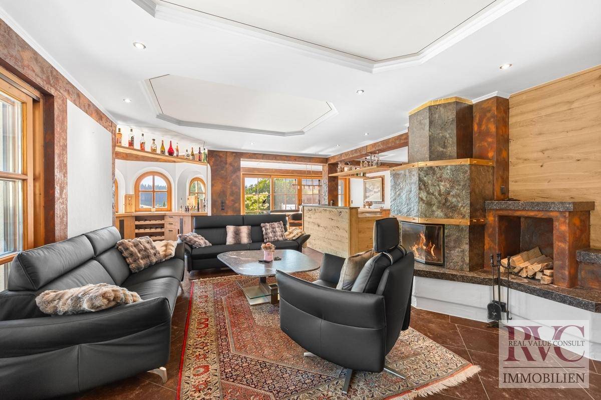 Geräumiges Wohnzimmer mit Kamin, Ledersofas und einem eleganten Couchtisch auf einem Orientteppich.
