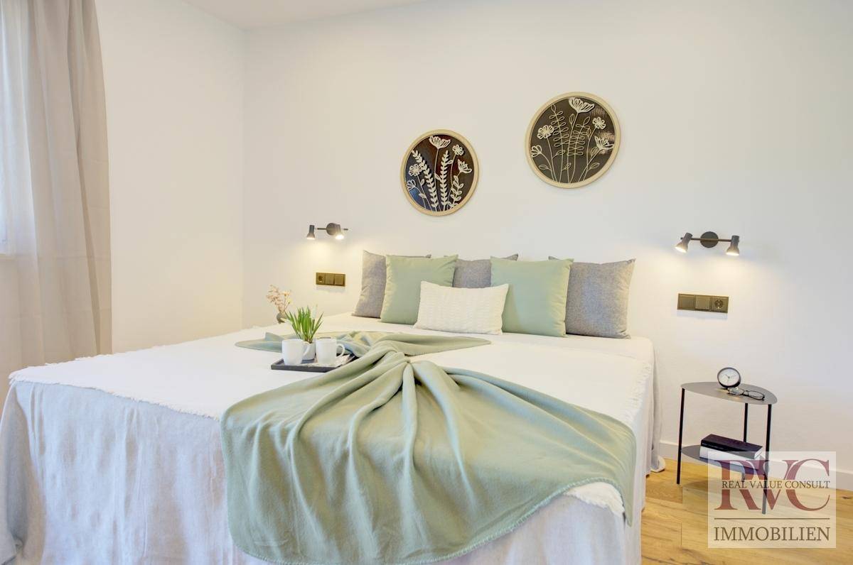 Helles Schlafzimmer mit großem Bett, modernen Wandleuchten und dekorativen Elementen an der Wand.