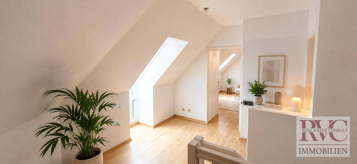 Heller Flurbereich mit Dachschräge, Dachfenster und Holzfußboden, der zu weiteren Räumen führt.