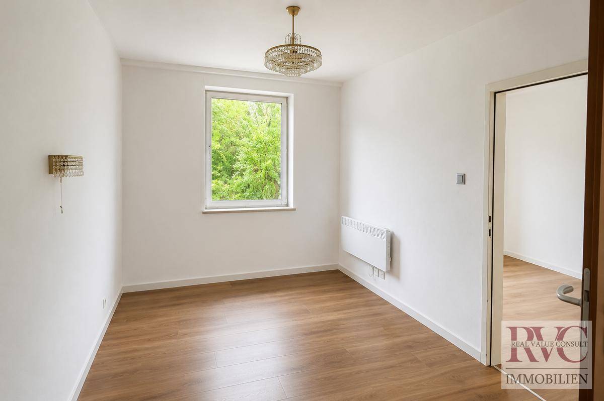 Ruhiges Schlafzimmer mit Holzboden und Fenster, das viel Tageslicht hereinlässt.