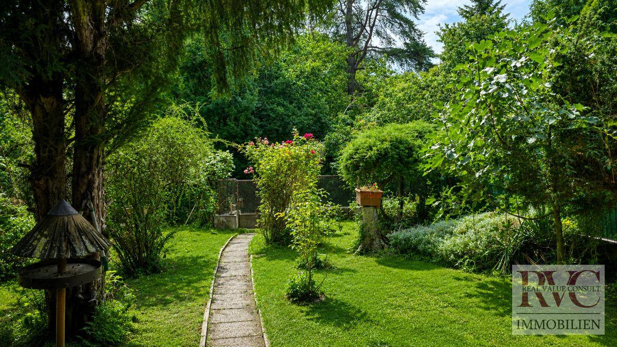 Gepflegter Garten mit Rasenflächen, Bäumen und einem Steinweg, der zum Entspannen einlädt.