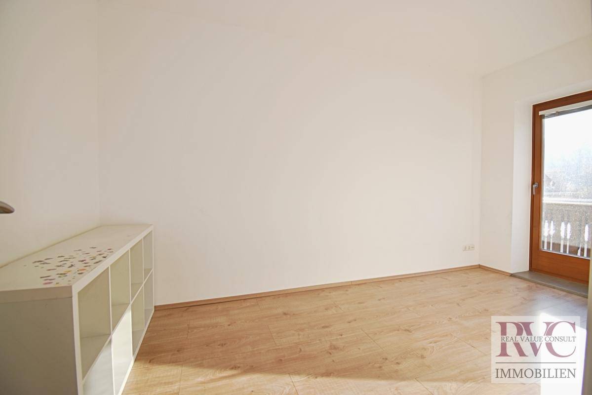 Leerer Raum mit hellem Laminatboden und Balkonzugang, bietet vielseitige Nutzungsmöglichkeiten.
