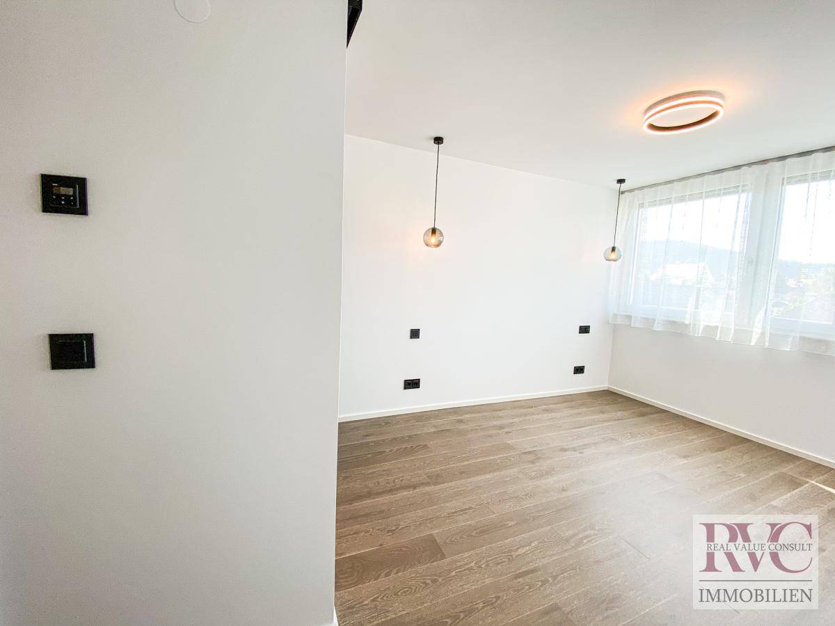 Geräumiges Schlafzimmer mit großen Fenstern, Holzboden und moderner Beleuchtung.