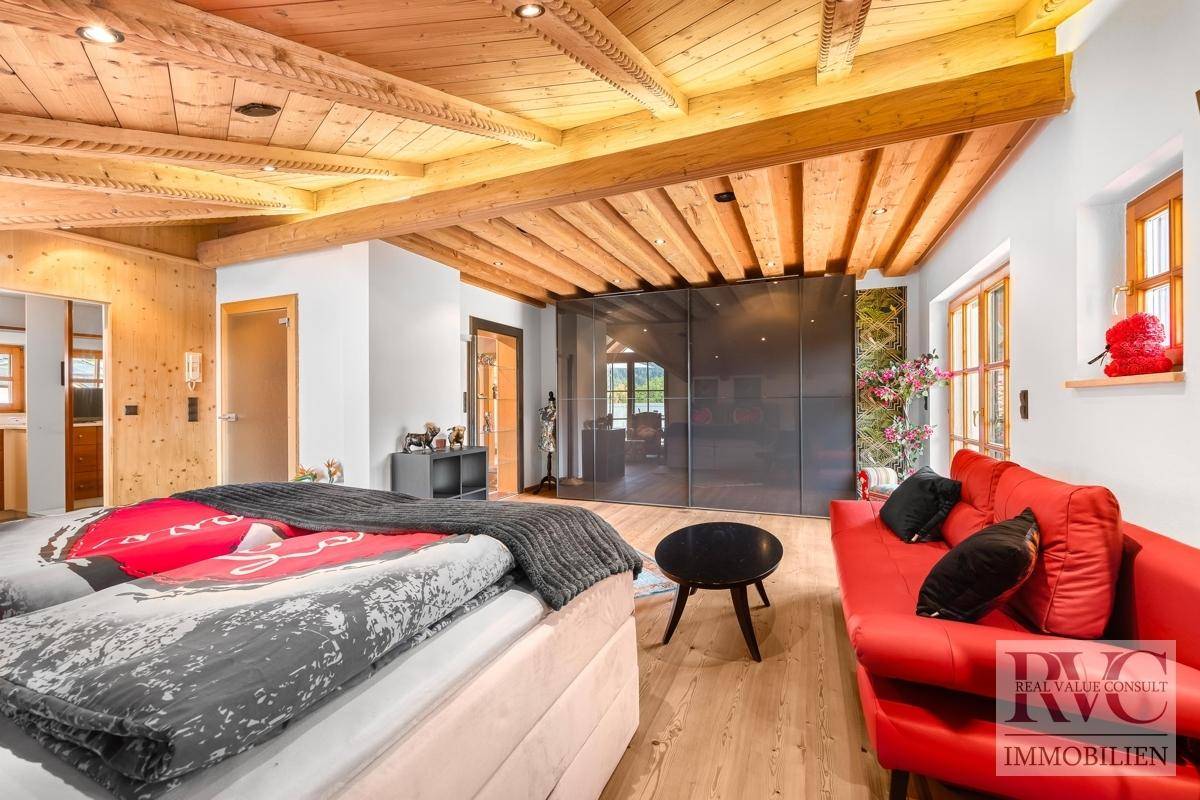 Geräumiges Schlafzimmer mit Holzbalkendecke, großem Kleiderschrank und rotem Sofa.