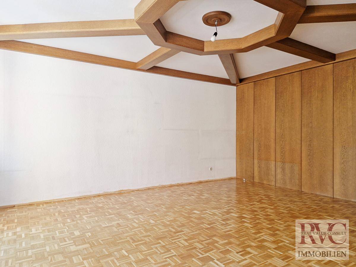 Geräumiges Wohnzimmer mit Holzbalkendecke und Parkettboden.