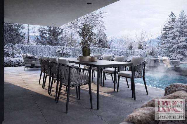 Stilvolle Terrasse mit großem Esstisch, modernen Stühlen und Blick auf den Pool und die Winterlandschaft.