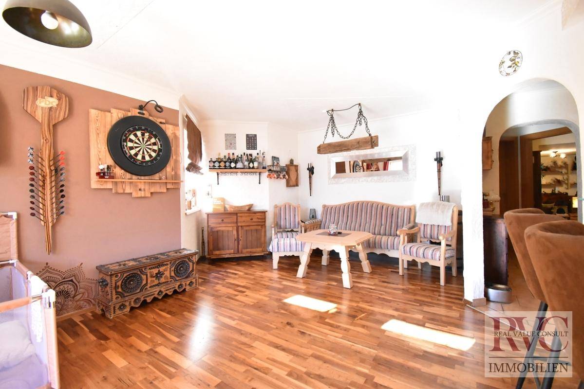 Gemütlicher Wohnbereich mit Holzboden, traditionellen Möbeln und einem Dartboard an der Wand.