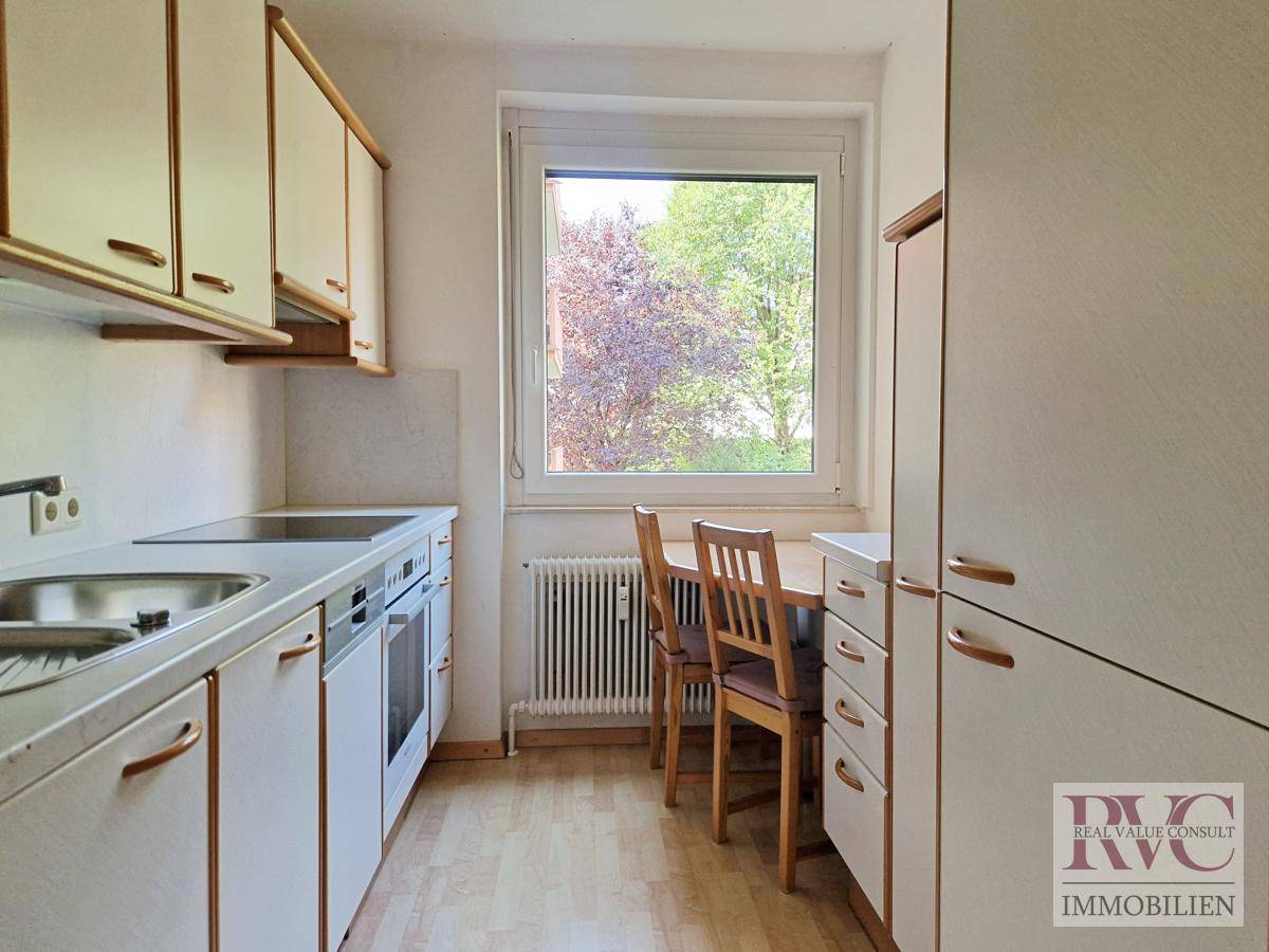 Funktionale Küche mit Einbauschränken, Fenster und Essbereich.