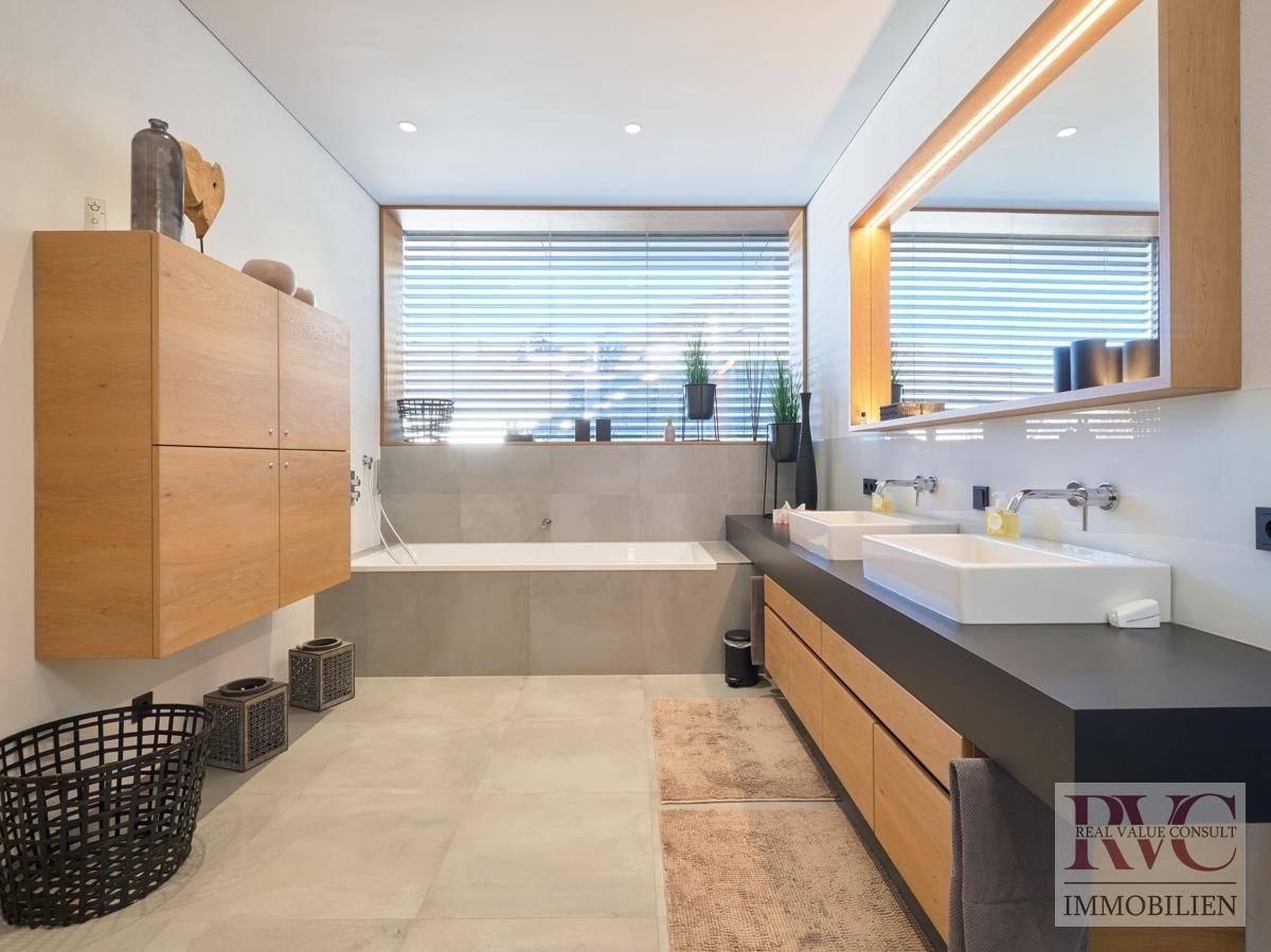 Modernes Badezimmer mit Doppelwaschbecken, Badewanne und schwebenden Holzschränken.