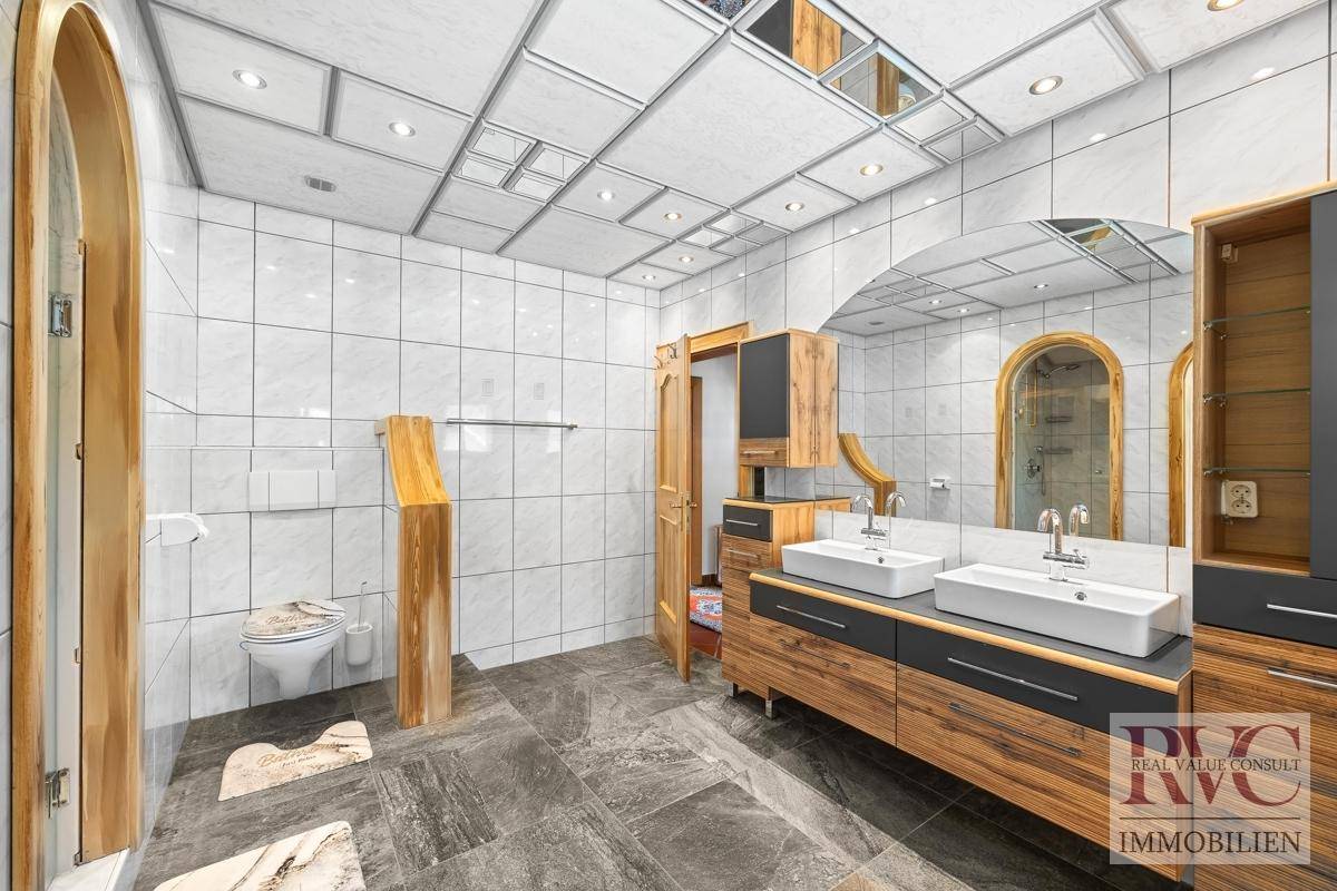 Geräumiges Badezimmer mit Doppelwaschbecken, Toilette und großem Spiegel.