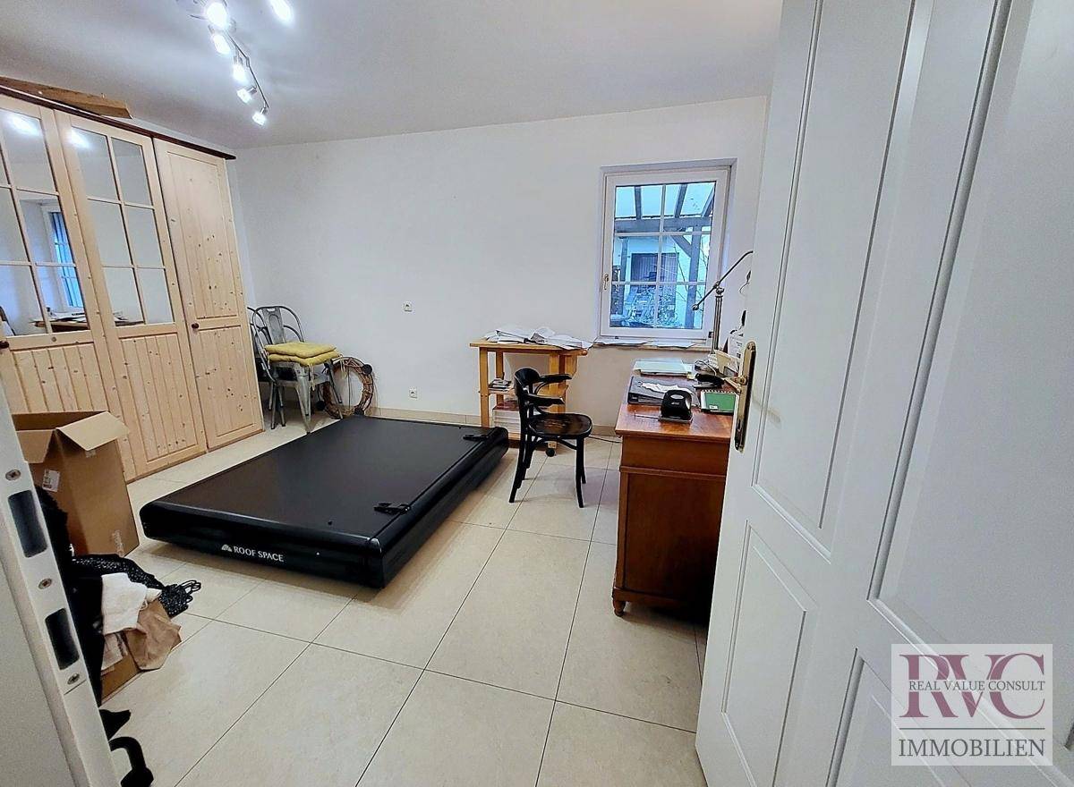 Arbeitszimmer mit Schreibtisch, Stuhl, Kleiderschrank und einem großen Bodenpolster.