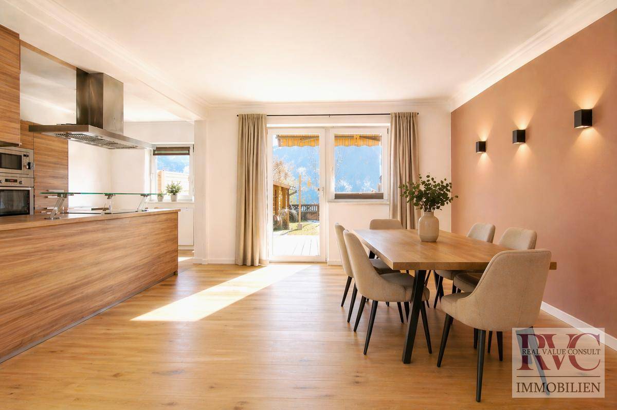 Heller Essbereich mit Holztisch, modernen Stühlen und offener Küche mit Zugang zum Garten.