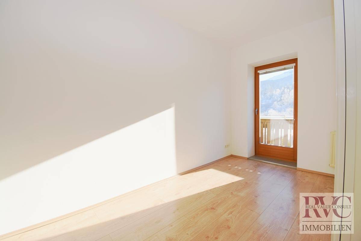 Helles Zimmer mit Balkonzugang, Laminatboden und Bergblick.