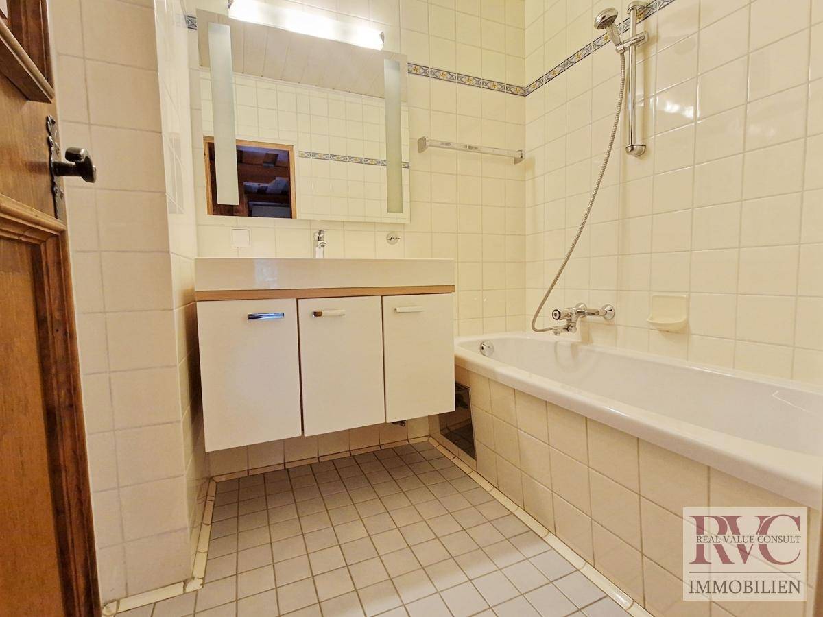 Gefliestes Badezimmer mit Badewanne, Waschbecken und Spiegel.