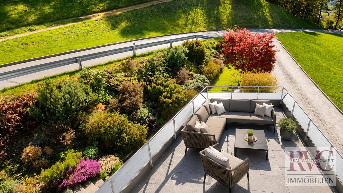 Obere Terrasse mit modernen Loungemöbeln und Blick auf die vielfältige Bepflanzung.