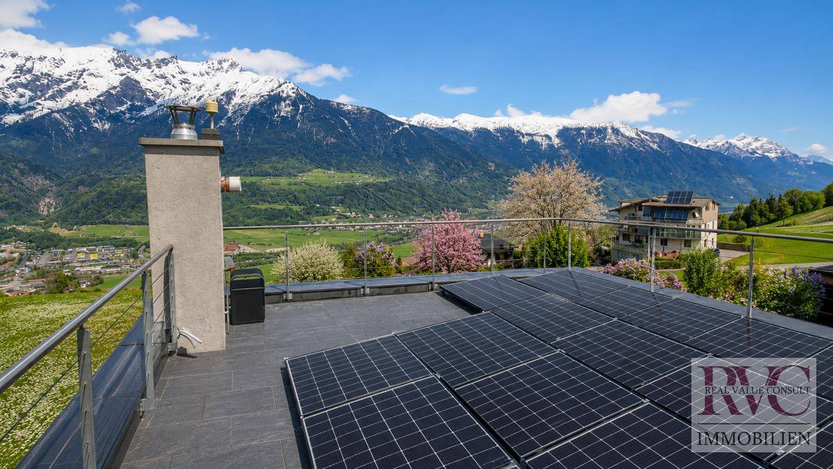 Dachterrasse mit Photovoltaikanlage und weitem Blick auf die umliegende Bergwelt.