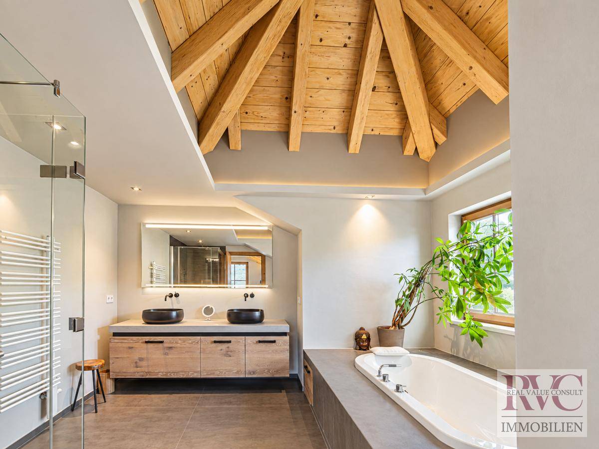 Modernes Badezimmer mit Holzbalkendecke, Doppelwaschbecken und Badewanne.