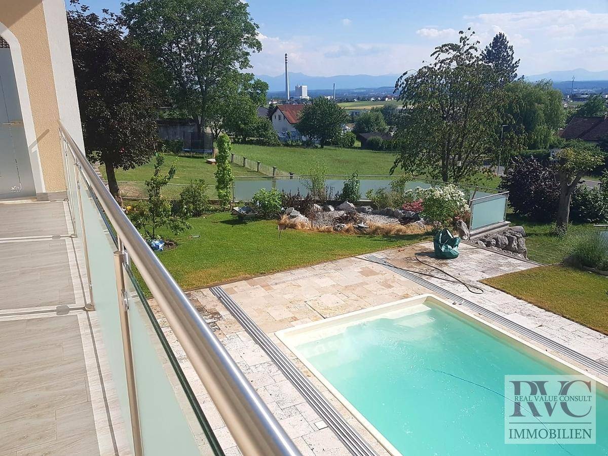 Außenbereich mit Swimmingpool, gepflegtem Rasen und weitem Blick in die Landschaft.