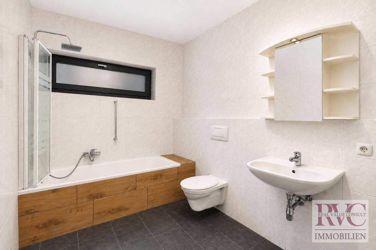 Modernes Badezimmer mit Badewanne, Dusche, WC und Fenster.