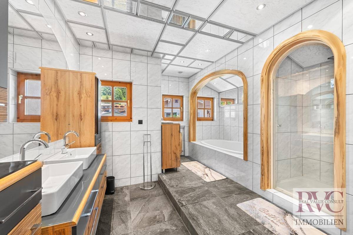 Modernes Badezimmer mit Doppelwaschbecken, Dusche, Badewanne und hellen Fliesen.