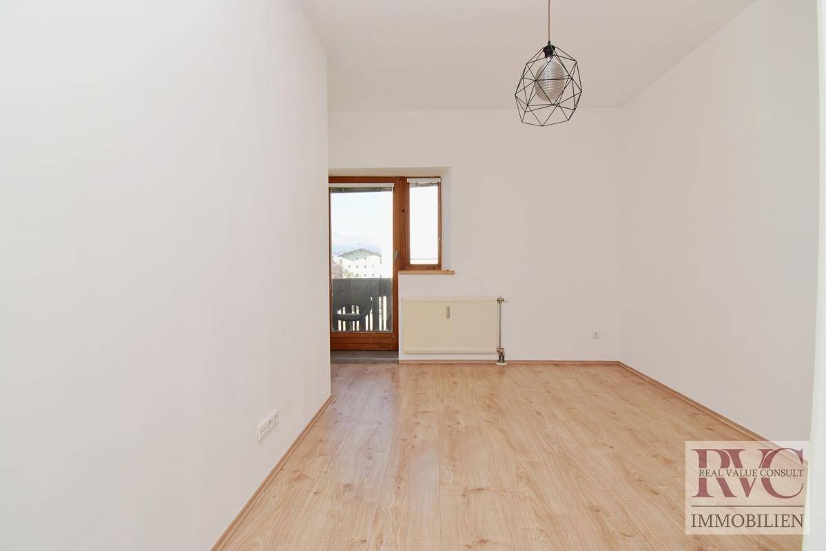 Leerer Raum mit hellem Laminatboden, Fenster und Balkonzugang, ideal für individuelle Nutzung.
