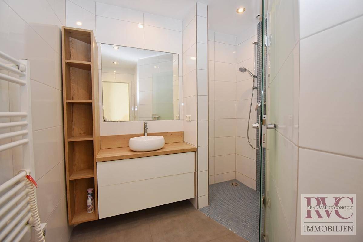 Modernes Badezimmer mit ebenerdiger Dusche, stilvollem Waschtisch und beheiztem Handtuchhalter.