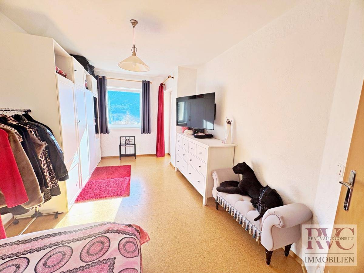 Geräumiges Schlafzimmer mit viel Stauraum, Fernseher und hellem Korkboden.