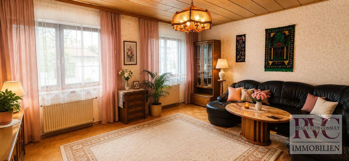 Traditionelles Wohnzimmer mit bequemer Ledercouch, Teppich und großen Fenstern.