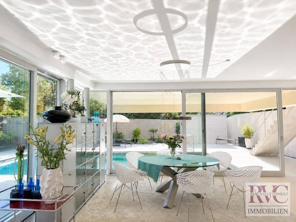 Heller Essbereich mit modernem Esstisch, Designerstühlen und Blick auf den Poolbereich.